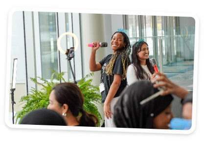Two Students standing back to back with microphones smiling