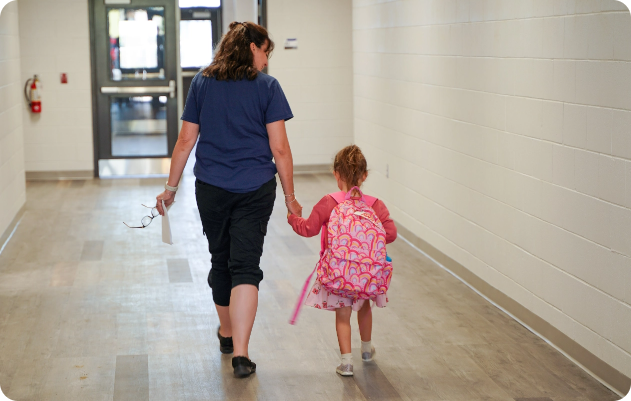 parent walking with child holding hands inside the school