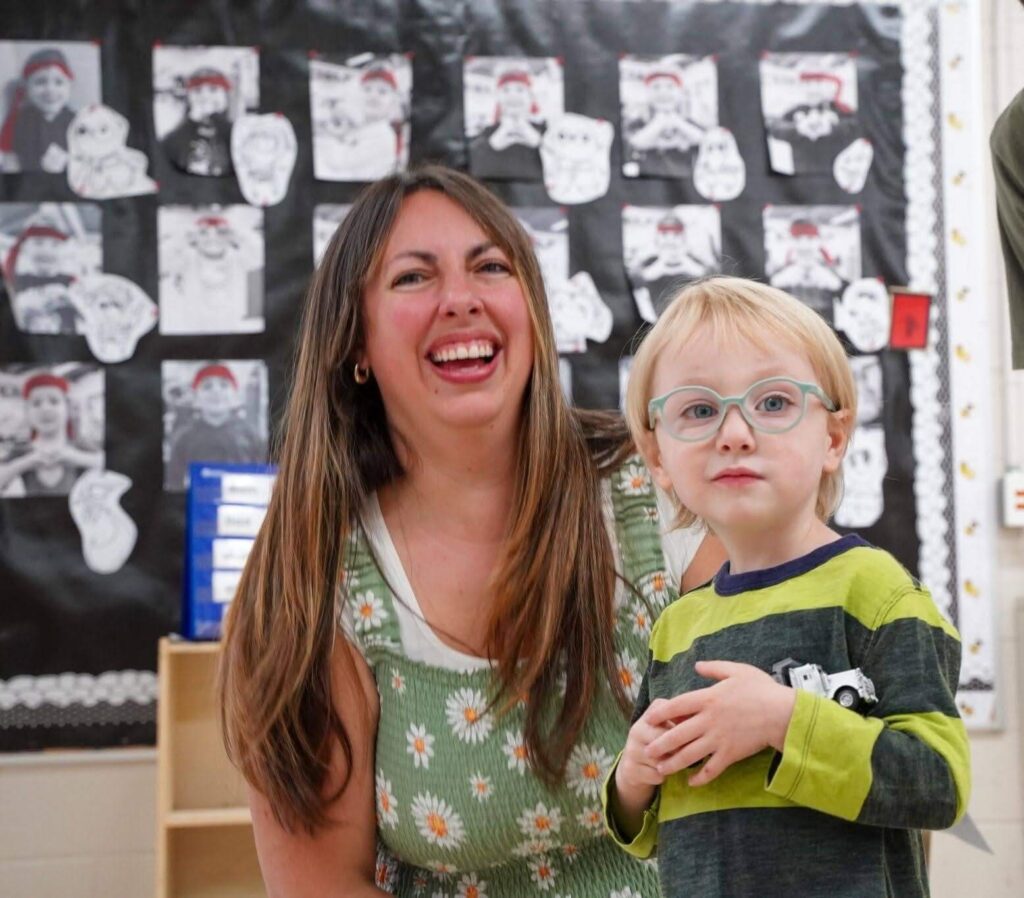 Family members visiting a classroom and participating in a learning activity with a young child.